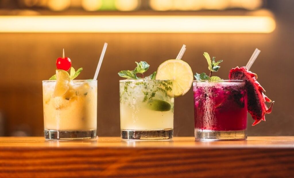Kolme koristeellista alkoholitonta cocktailia puupöydällä