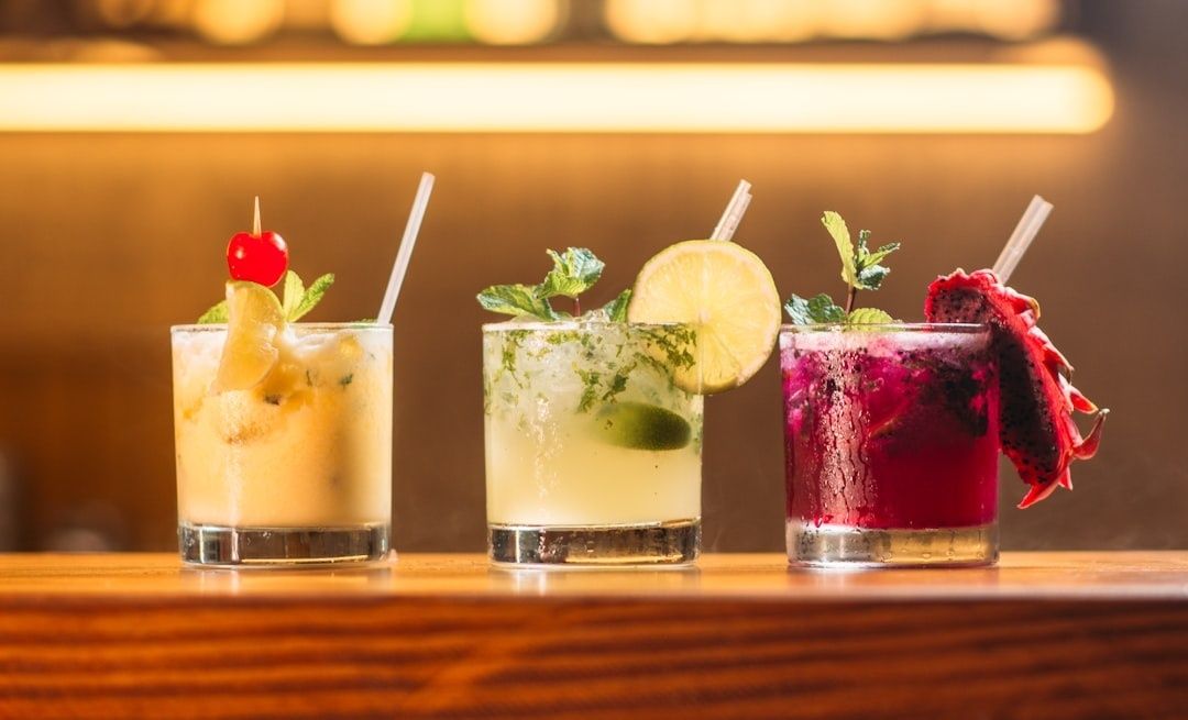 Kolme koristeellista alkoholitonta cocktailia puupöydällä